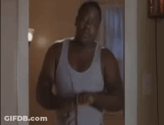 Man In Tank Top Holding Scissors In Doorway GIF
