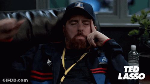 Man In Ted Lasso Jacket Sitting On Couch GIF