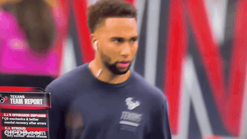 Man In Texans Shirt Standing By Team Report Sign GIF