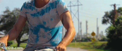 Man In Tie Dye Shirt Riding Bike GIF