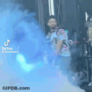 Man In Tie Dye Shirt With Blue Smoke Bomb GIF