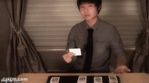 Man In Tie Holding Card In Front Of Table Of Cards GIF