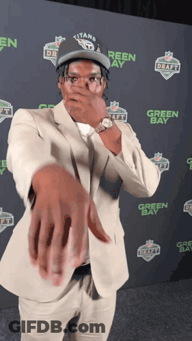 Man In Titans Hat Covering Mouth GIF