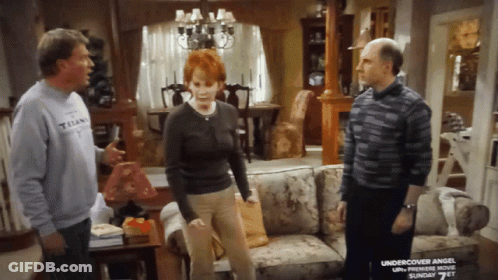 Man In Titans Shirt Talks To Woman And Man In Living Room GIF