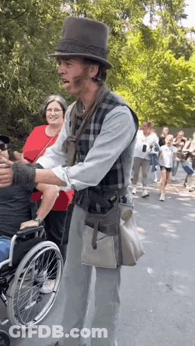 Man In Top Hat Standing Next To Man In Wheelchair GIF