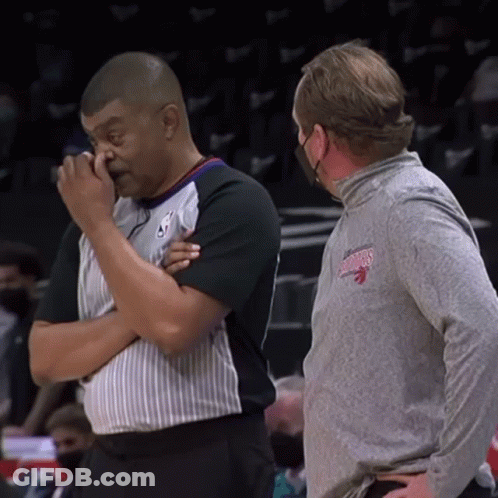 Man In Toronto Raptors Shirt Wiping Nose Talking To Another Man GIF