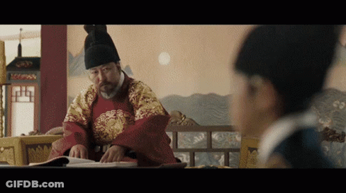 Man In Traditional Costume Reading Book, Another Looking On GIF