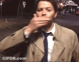 Man In Trench Coat And Tie Covering Mouth GIF