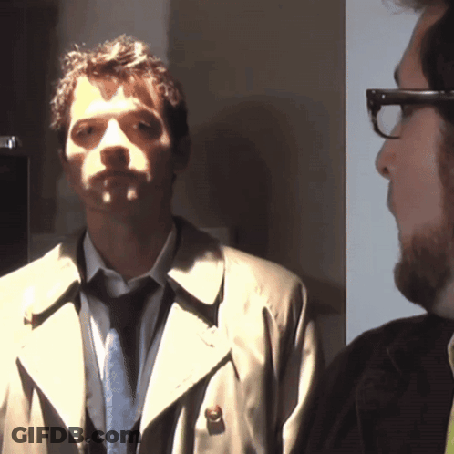 Man In Trench Coat And Tie Next To Man In Glasses GIF