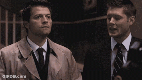 Man In Trench Coat And Tie Next To Man In Suit GIF