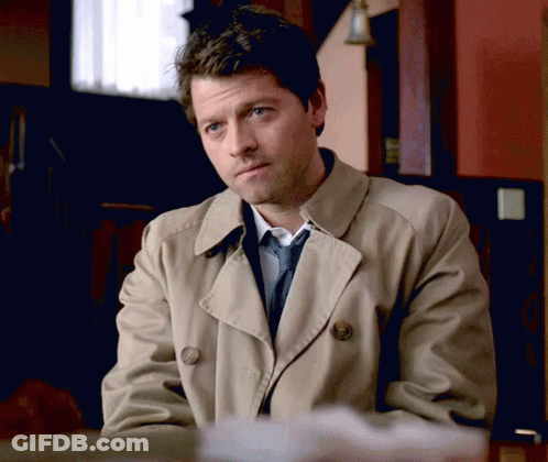 Man In Trench Coat And Tie Sitting At Desk GIF