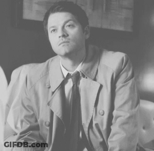 Man In Trench Coat And Tie Sitting On Couch GIF