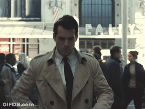 Man In Trench Coat In Front Of Calif Building GIF