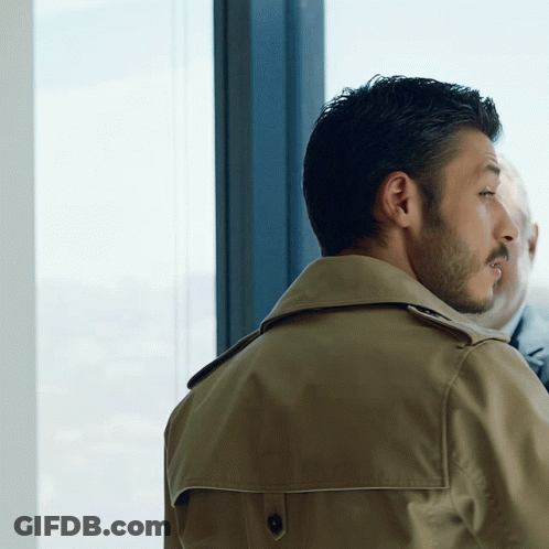 Man In Trench Coat Looking Out Window GIF