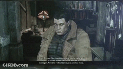 Man In Trench Coat Sitting In Dark Room Talking To Another Man GIF