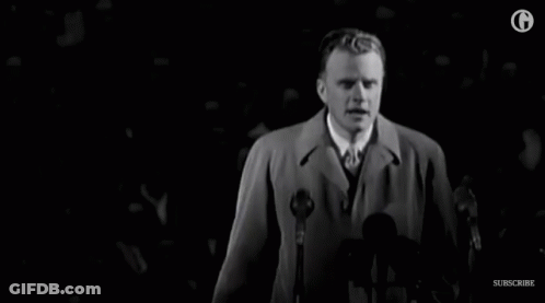 Man In Trench Coat Speaking Into Microphone GIF