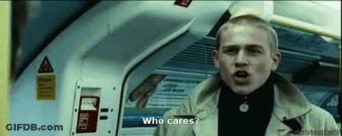 Man In Trench Coat Talking On Train Asking Who Cares GIF
