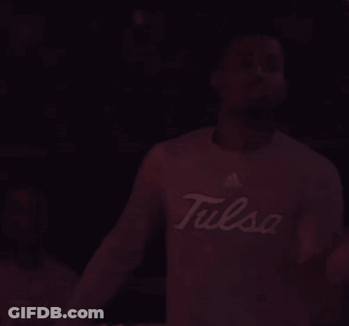 Man In Tulsa Shirt Standing In Dark Room GIF