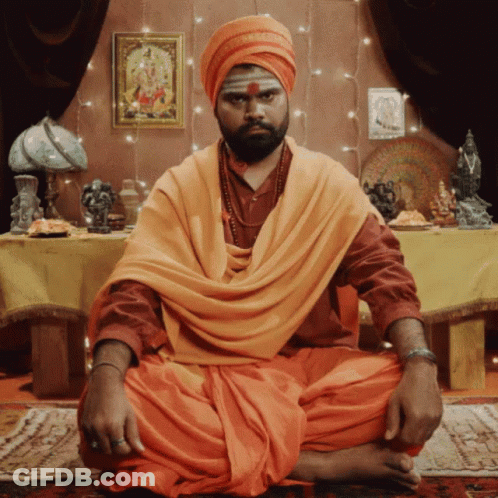 Man In Turban And Orange Robe At Table GIF