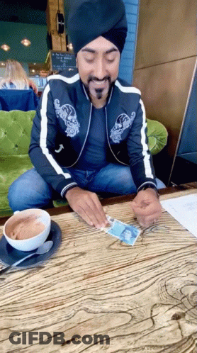 Man In Turban Sitting At Table With Coffee And Paper GIF