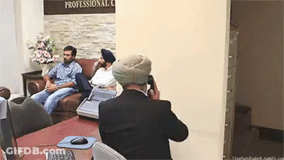 Man In Turban Taking Picture Of Group In Front Of Professional Sign GIF