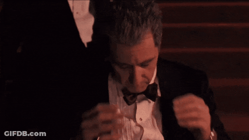 Man In Tuxedo Adjusting Bow Tie In Dark Room GIF