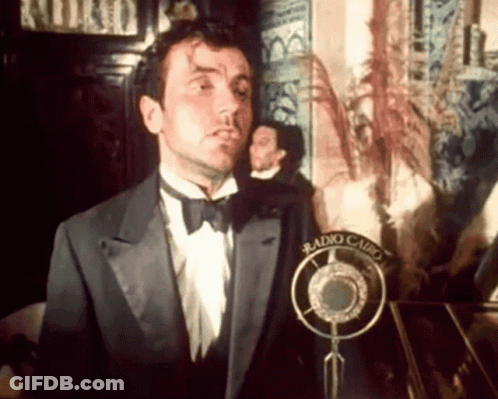 Man In Tuxedo And Bow Tie At Microphone GIF