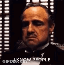 Man In Tuxedo And Bow Tie Sitting In Front Of Window GIF