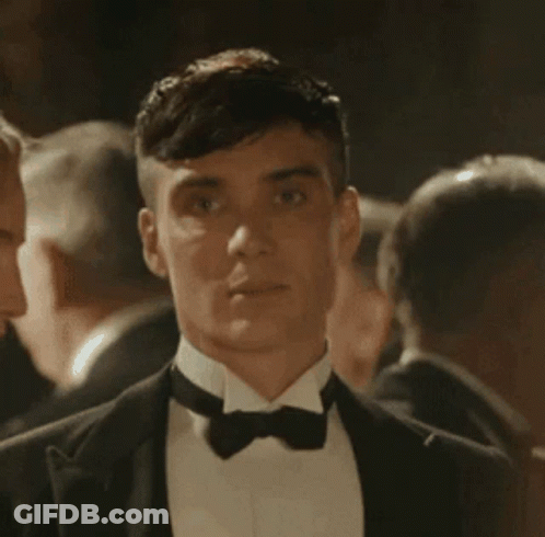 Man In Tuxedo And Bow Tie Standing In Crowd GIF