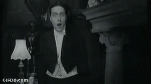 Man In Tuxedo And Bow Tie Standing In Front Of Lamp GIF