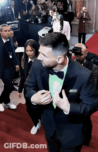 Man In Tuxedo And Bow Tie Walking Down Red Carpet GIF