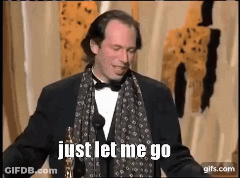Man In Tuxedo And Scarf Holding Oscar At Microphone GIF