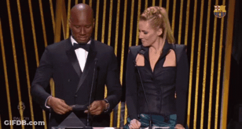 Man In Tuxedo And Woman In Black Dress At Microphones GIF