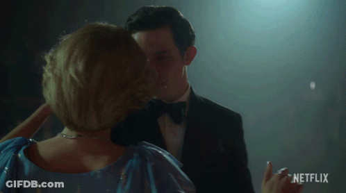 Man In Tuxedo And Woman In Blue Dress Dancing With Netflix Logo GIF