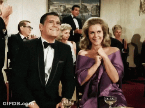 Man In Tuxedo And Woman In Purple Dress Sitting At Table GIF