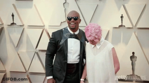 Man In Tuxedo And Woman With Pink Hair Posing GIF