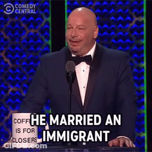 Man In Tuxedo At Podium With He Married An Immigrant Mug GIF