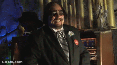 Man In Tuxedo Clapping In Front Of Statue GIF