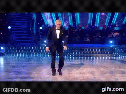 Man In Tuxedo Dancing In Front Of Orchestra GIF