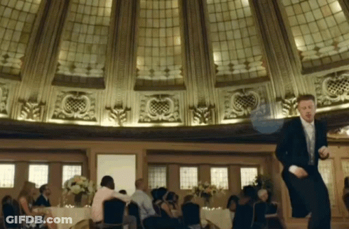 Man In Tuxedo Dancing In Room With People At Tables GIF