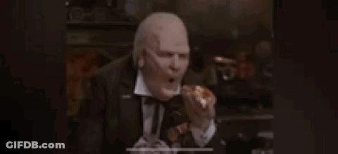 Man In Tuxedo Eating Hamburger In Dark Room GIF