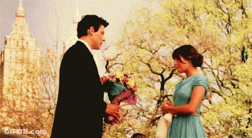 Man In Tuxedo Giving Woman Flowers GIF
