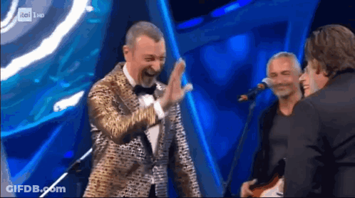 Man In Tuxedo High Fives Another Man At Mic GIF
