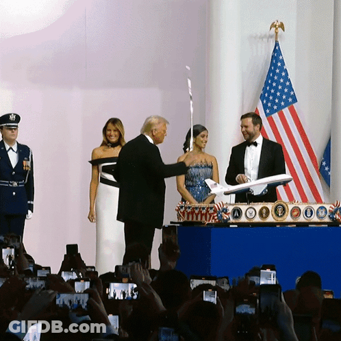 Man In Tuxedo Holding Airplane Before Crowd GIF