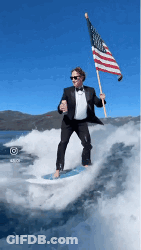 Man In Tuxedo Holding American Flag Riding Wave GIF