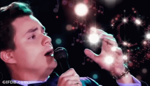Man In Tuxedo Holding Mic And Wine GIF