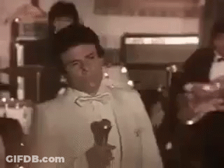 Man In Tuxedo Holding Microphone And Wine GIF