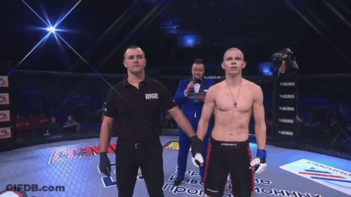 Man In Tuxedo Holding Microphone In Front Of Man In Black Panasonic Shirt GIF