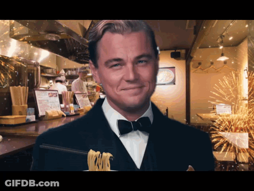 Man In Tuxedo Holding Noodles And Smiling GIF