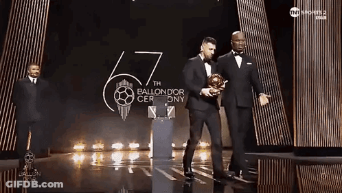 Man In Tuxedo Holding Soccer Ball On Stage GIF